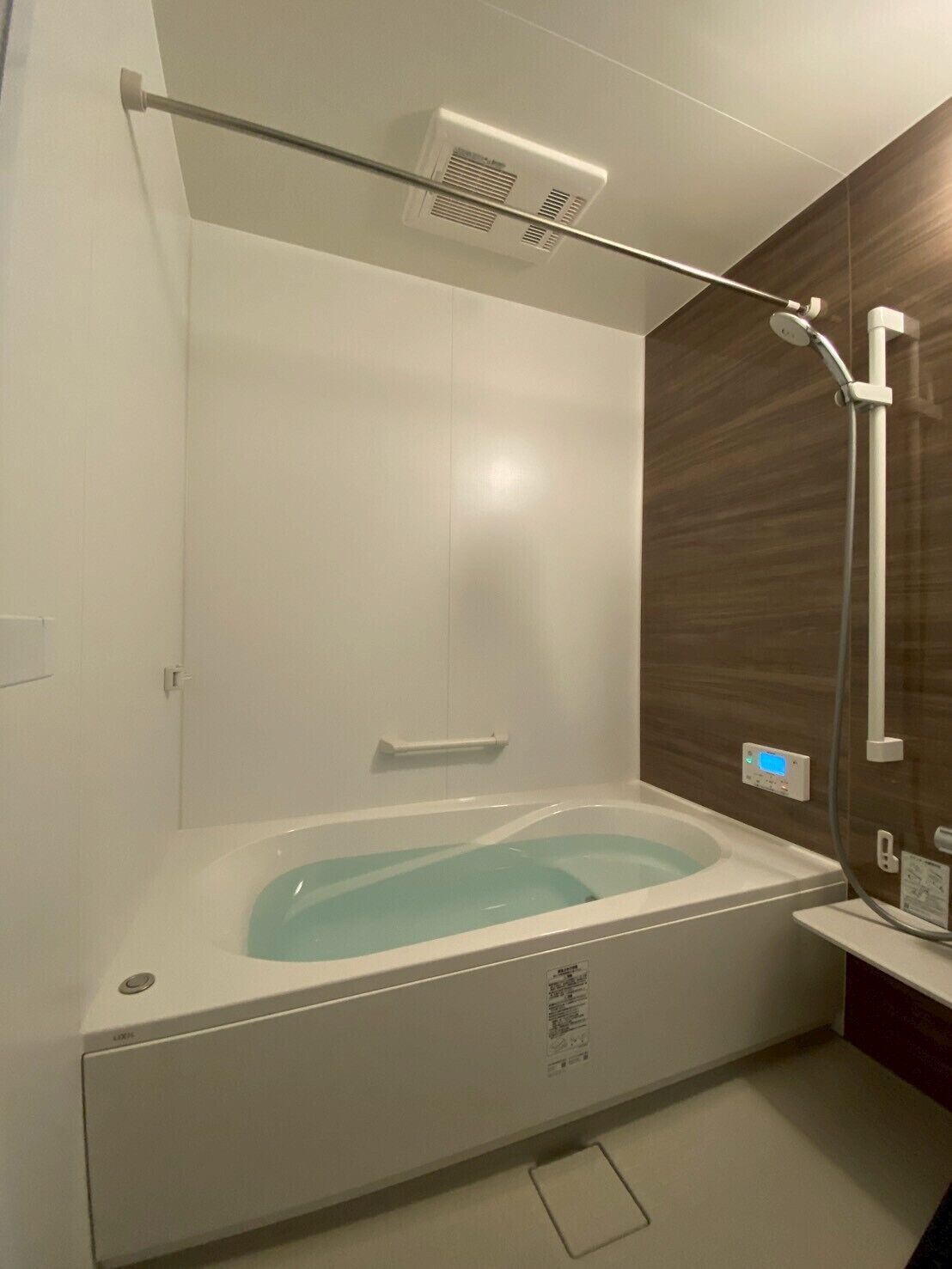 A modern bathroom with a freestanding bathtub, a showerhead, and a control panel.
