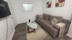 A living room with a sofa, a coffee table, a TV, and a window. - Delightful 3-bedroom apartment in Montréal perfect for your stay (Montréal)