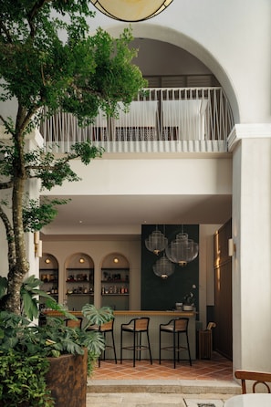 A two-story building with a balcony, a bar area with chairs, and a large tree in the foreground. - Cheong Fatt Tze - The Qing Suites (George Town)