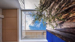 A modern interior with a geometric ceiling design, a view of the sky through a window, and a wooden wall. - Cheong Fatt Tze - The Qing Suites (George Town)