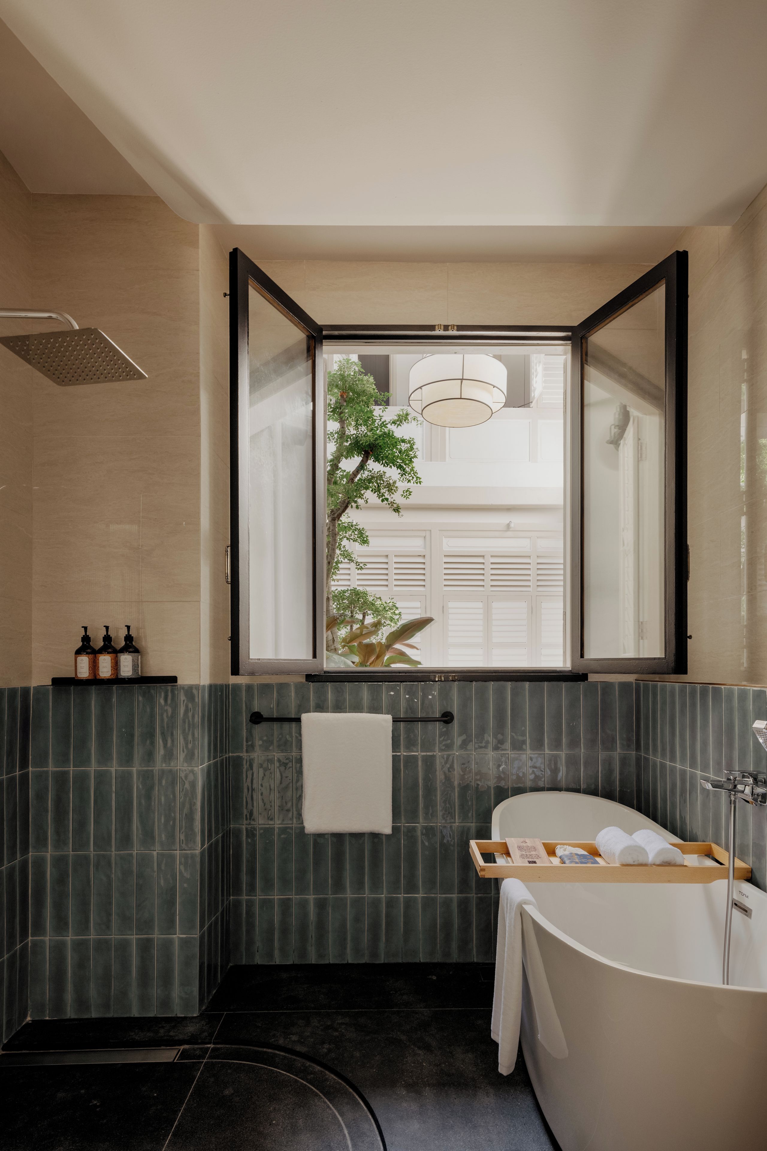Une salle de bain moderne avec une baignoire sur pieds, un grand miroir et une fenêtre donnant sur un immeuble et de la verdure.