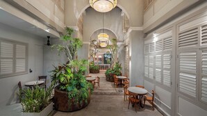 A corridor with a central walkway, flanked by seating areas and potted plants, leading to a bar area. - Cheong Fatt Tze - The Qing Suites (George Town)