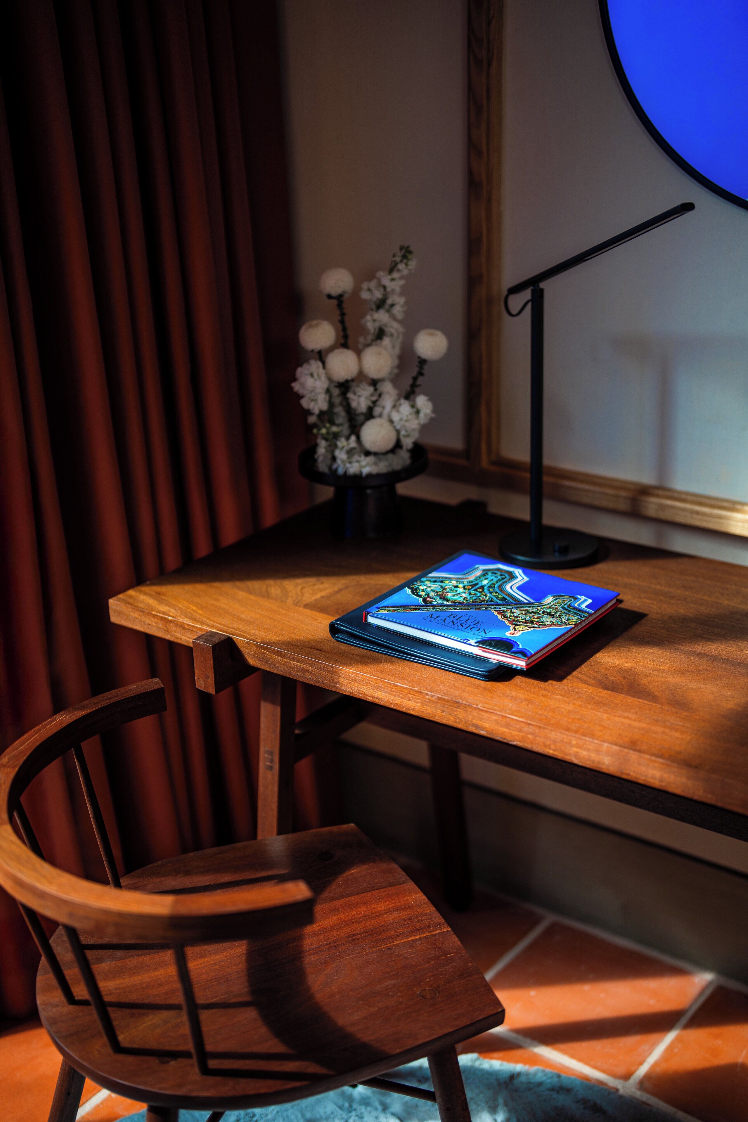 A wooden table with a notebook, a chair, a vase with flowers, and a microphone stand.