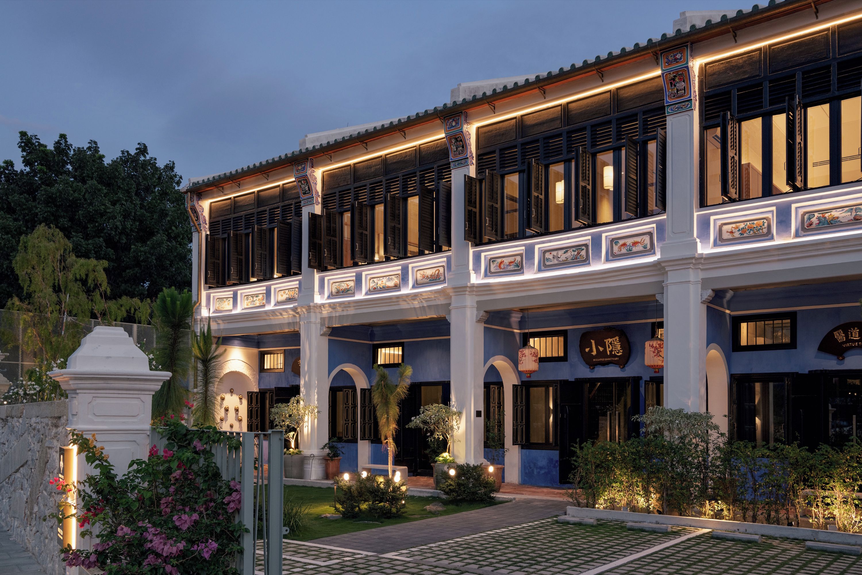 A traditional building with multiple balconies, a gated entrance, and a well-maintained garden.