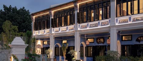 A traditional building with multiple balconies, a gated entrance, and a well-maintained garden.
