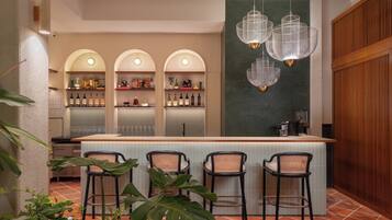A bar area with a counter, three shelves of bottles, and four bar stools.