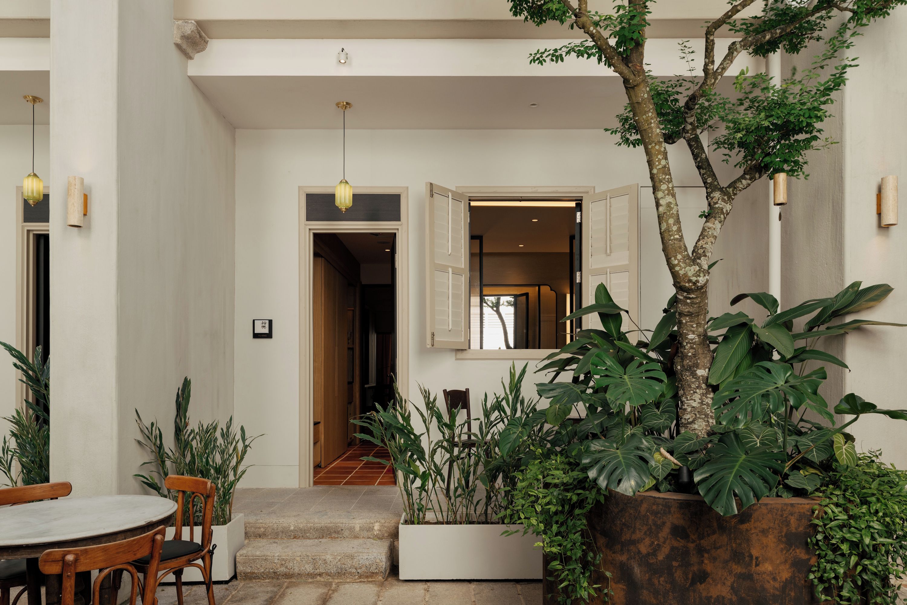 A courtyard with a dining area, a staircase, and a variety of plants.