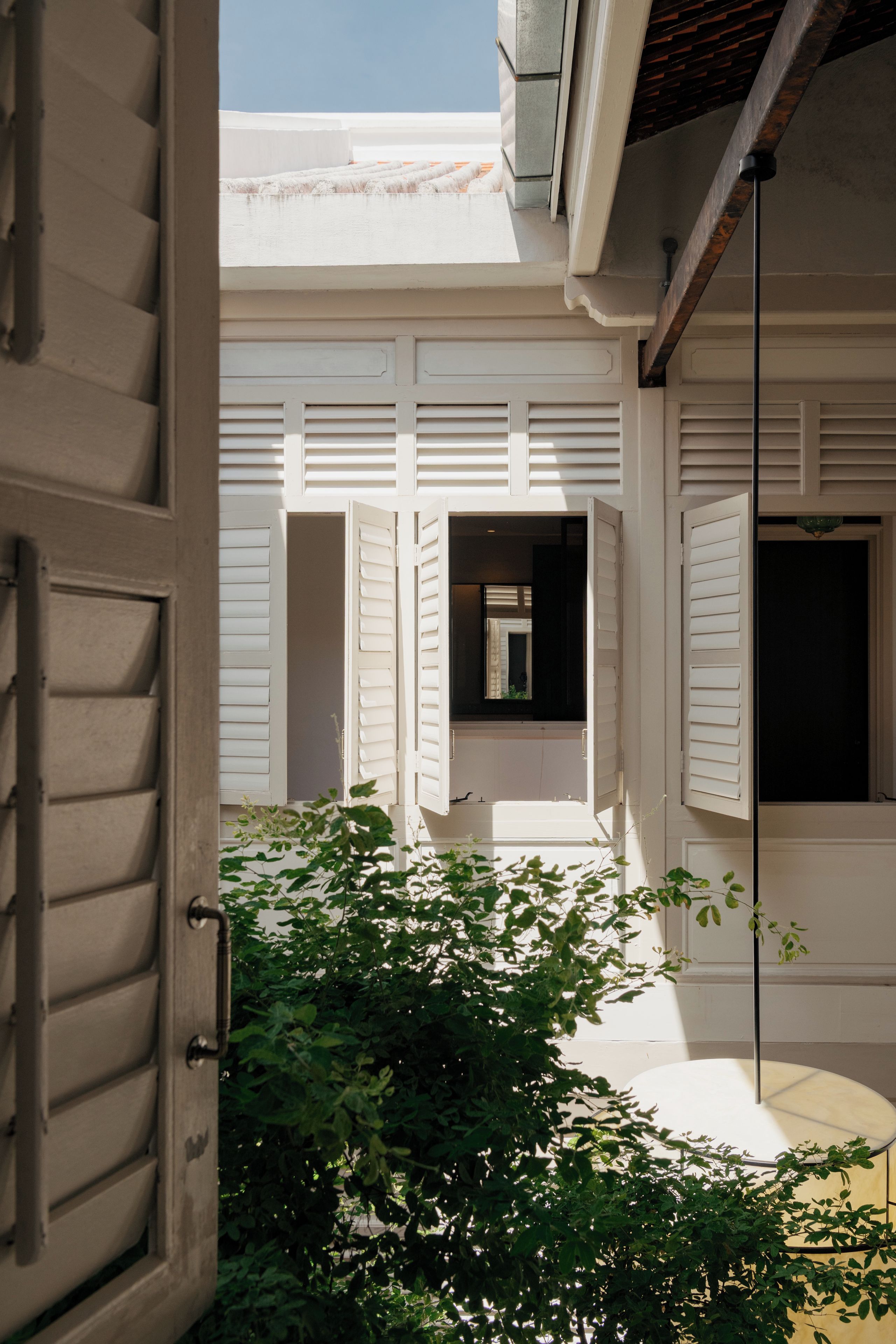 A courtyard with a white door, a window with shutters, and a small table.