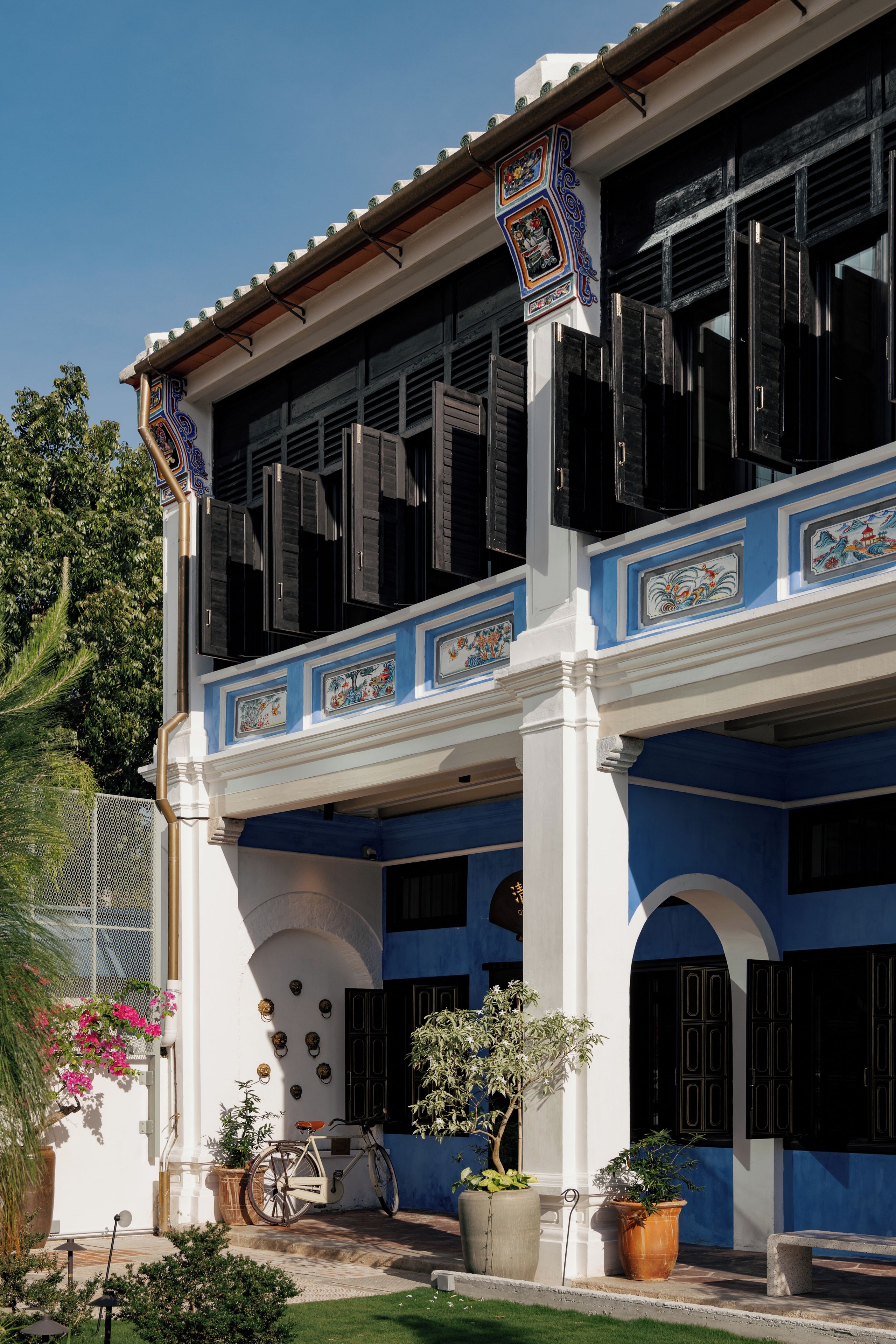 A two-story building with a balcony, large windows, and decorative tiles.