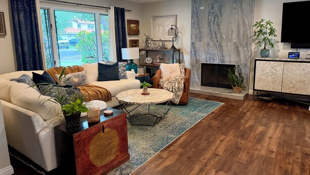 Een moderne woonkamer met een bank, fauteuil, salontafel en open haard.