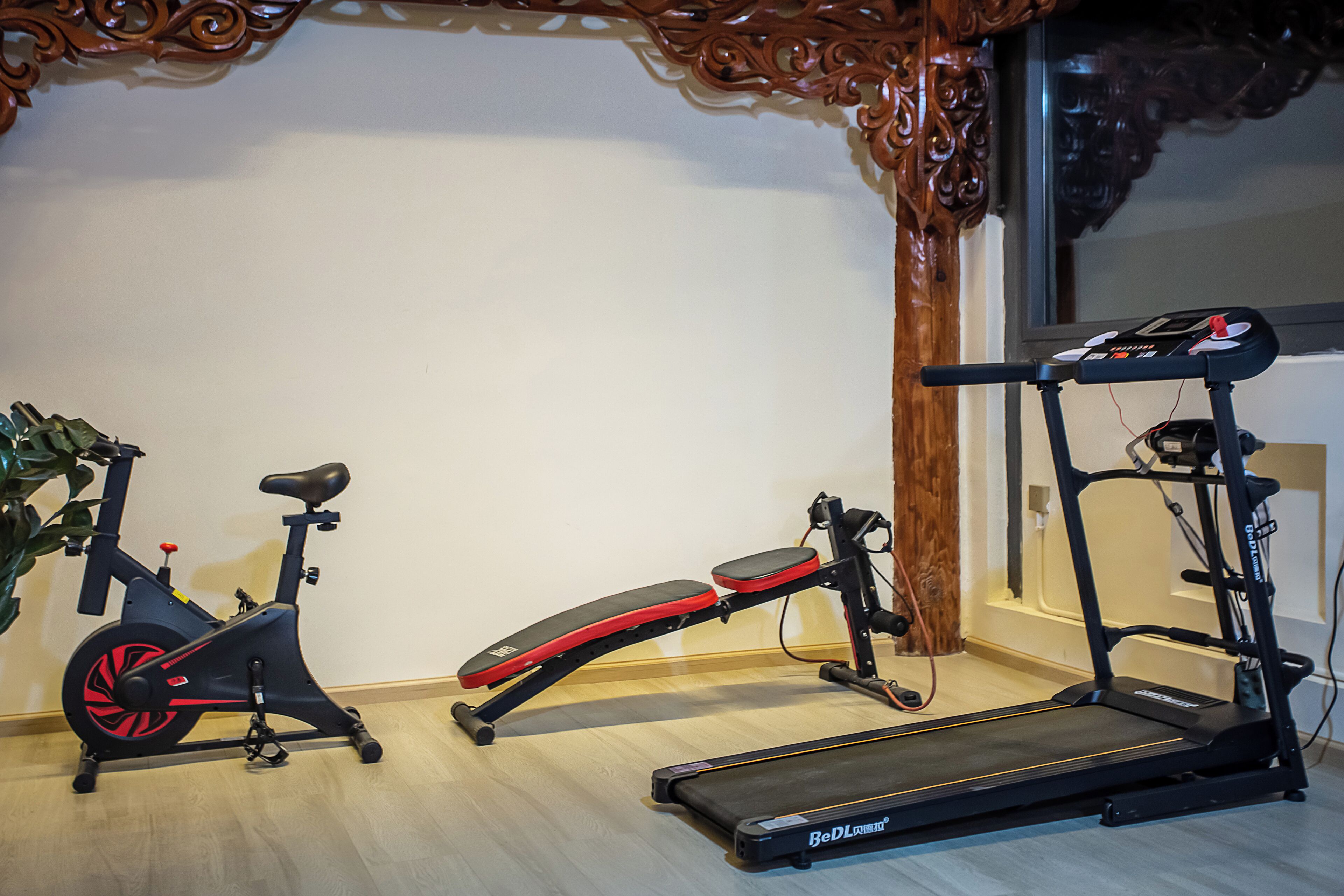 Un gimnasio en casa con una bicicleta estática, una banca y una cinta de correr.