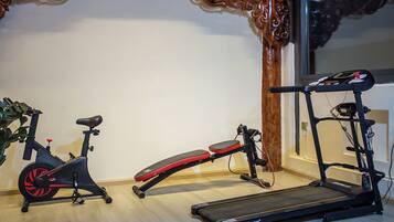 Un gimnasio en casa con una bicicleta estática, una banca y una cinta de correr.