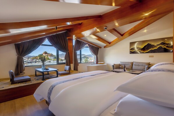 A bedroom with a large bed, a desk, a chair, a sofa, and a view of a mountain.