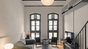 Ein modernes Wohnzimmer mit einer Couch, zwei Sesseln, einem Couchtisch, einem Fernseher und einer Treppe.