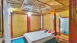 Une pièce comprenant un lit, un ventilateur de plafond, un miroir et un petit banc en bois.