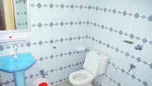 Une salle de bain avec un lavabo bleu, des toilettes blanches et des carreaux décoratifs sur les murs.