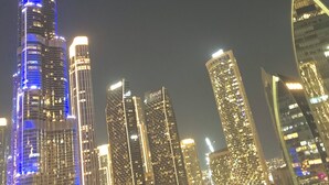 Paisagem urbana noturna com um arranha-céu em destaque, iluminado em azul.