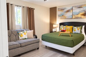 Ein Hotelzimmer mit einem Bett, einer Couch, einem Beistelltisch und einer Wandlampe.