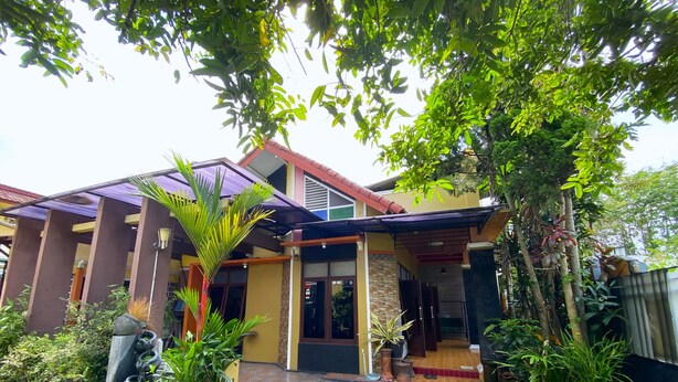 A modern house with a tiled entrance, surrounded by lush greenery and a palm tree. - Homestay Jogja Dekat UII By Simply Homy (Ngaglik)