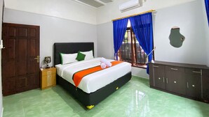 A bedroom with a bed, a wooden nightstand, a dresser, an air conditioning unit, and a window with blue curtains. - Homestay Jogja Dekat UII By Simply Homy (Ngaglik)
