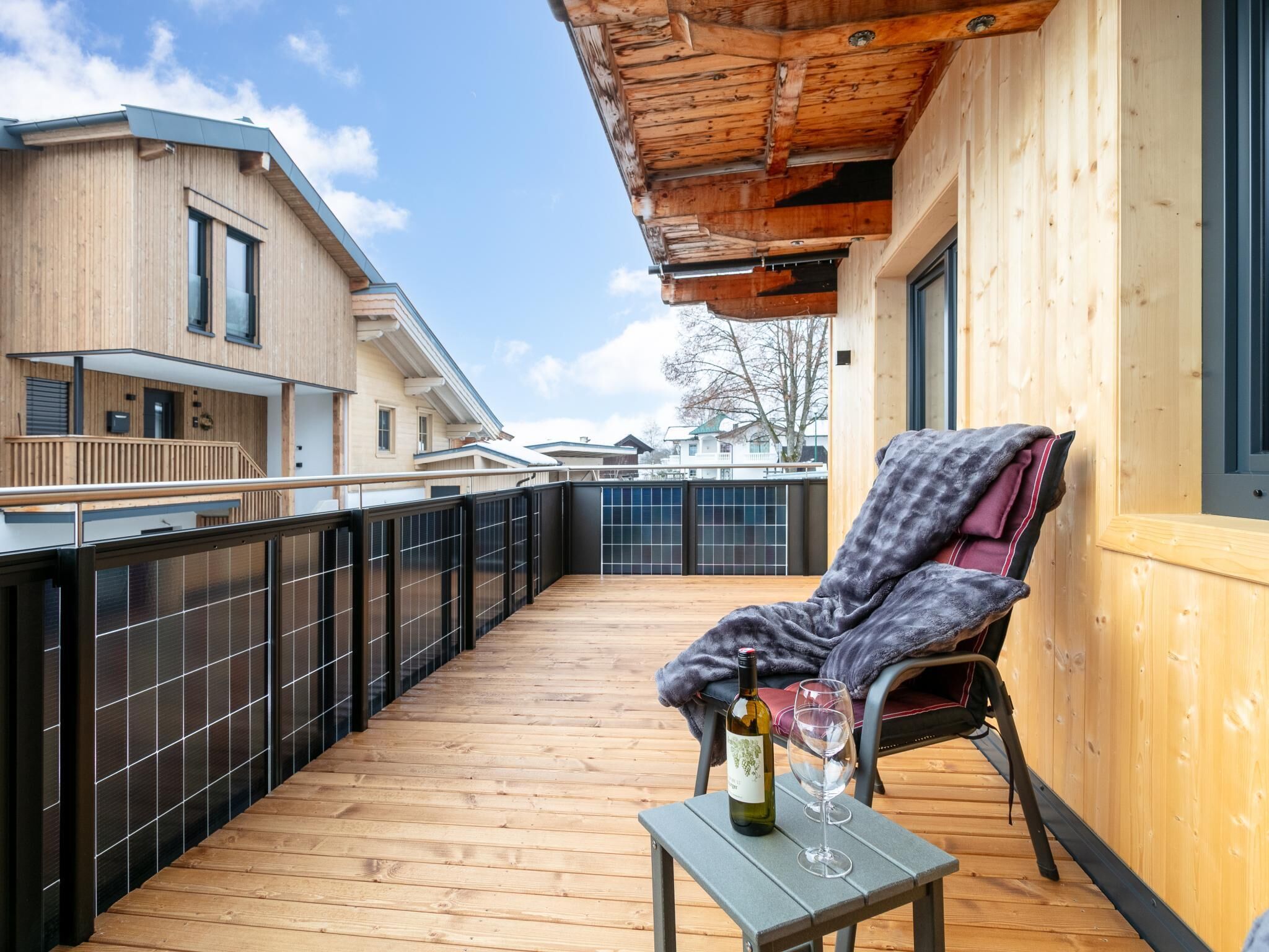 A wooden deck with a chair and a table holding a bottle and glass.