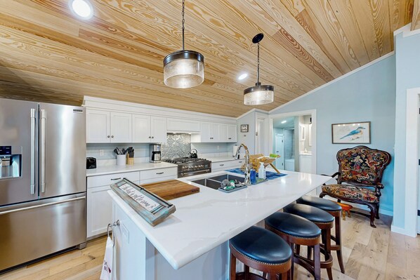 A modern kitchen with a large island, stainless steel appliances, and a wooden ceiling. - Historic Barn in Mississippi: Equestrian Getaway! (Tylertown)