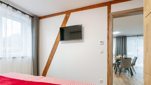 Ein Hotelzimmer mit Bett, einem an der Wand montierten Fernseher und Blick auf den Speisesaal.