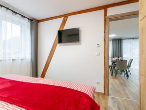 A hotel room with a bed, a TV mounted on the wall, and a view into the dining area. - Stylish holiday apartment in Brixen im Thale (Brixen im Thale)