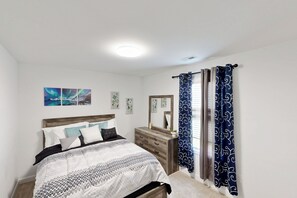 A bedroom with a bed, dresser, and curtains.
