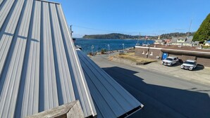 Uma estrada costeira com estrutura de telhado metálico, área de estacionamento e vista para o mar e terra distante.