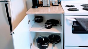 Uma cozinha compacta com geladeira branca, cafeteira, torradeira, chaleira e fogão.