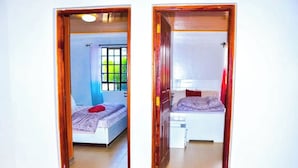 Two bedrooms with wooden doors, each with a bed, a window, and a curtain. - Majestic Airport Villa (Syokimau)