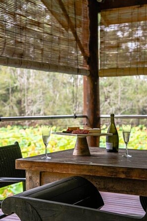 A wooden table with a bottle, glasses, and a plate of food. - Serene Overwater Villa - Romantic Escape for 2 (Lovedale)
