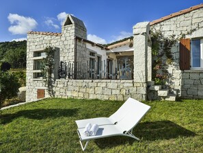 A stone building with a balcony and a white lounge chair with towels. - Li Conchi 44 – Dream Villa Surrounded by Nature Near Pool and Beach (Castiadas)