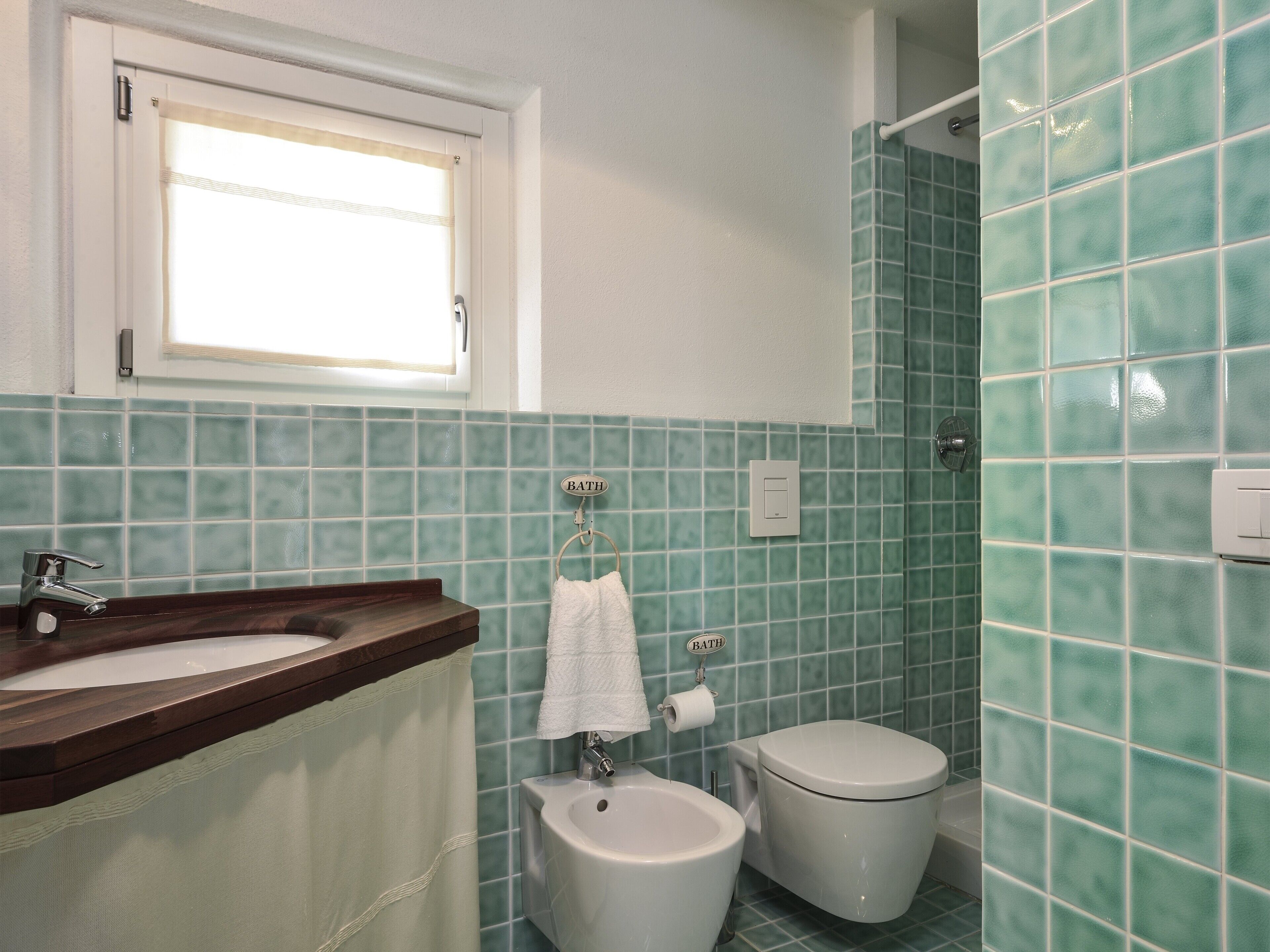 Une salle de bain avec un lavabo, des toilettes et une fenêtre.
