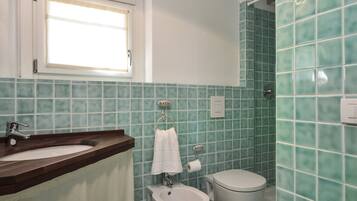Une salle de bain avec un lavabo, des toilettes et une fenêtre.