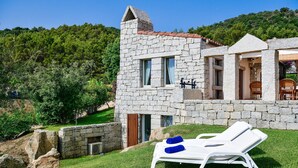 A stone building with a stone staircase, a wooden door, and a small window. - Li Conchi 35 – Spacious Holiday Home for 7 in a Modern Resort (Castiadas)
