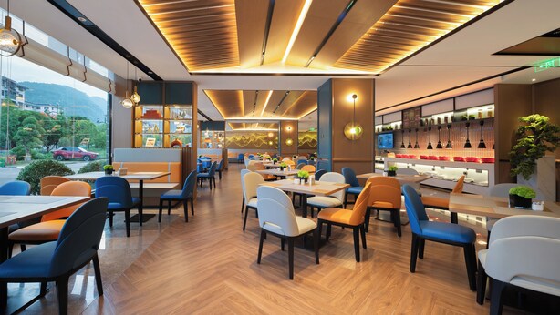 A modern restaurant interior with wooden flooring, multiple dining tables, and chairs. - Hampton by Hilton Zhangjiajie National Forest Park (Zhangjiajie)