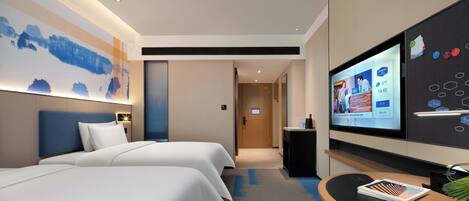 A hotel room with two beds, a desk with a flat-screen TV, and a large wall mural.