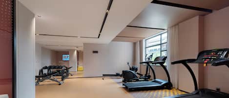 Een moderne sportschool met loopbanden, hometrainers en krachttoestellen.