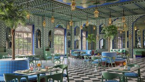Un restaurante con baldosas de piso a cuadros, asientos tipo cabina a cuadros en tonos verde y azul, y paredes con diseños.