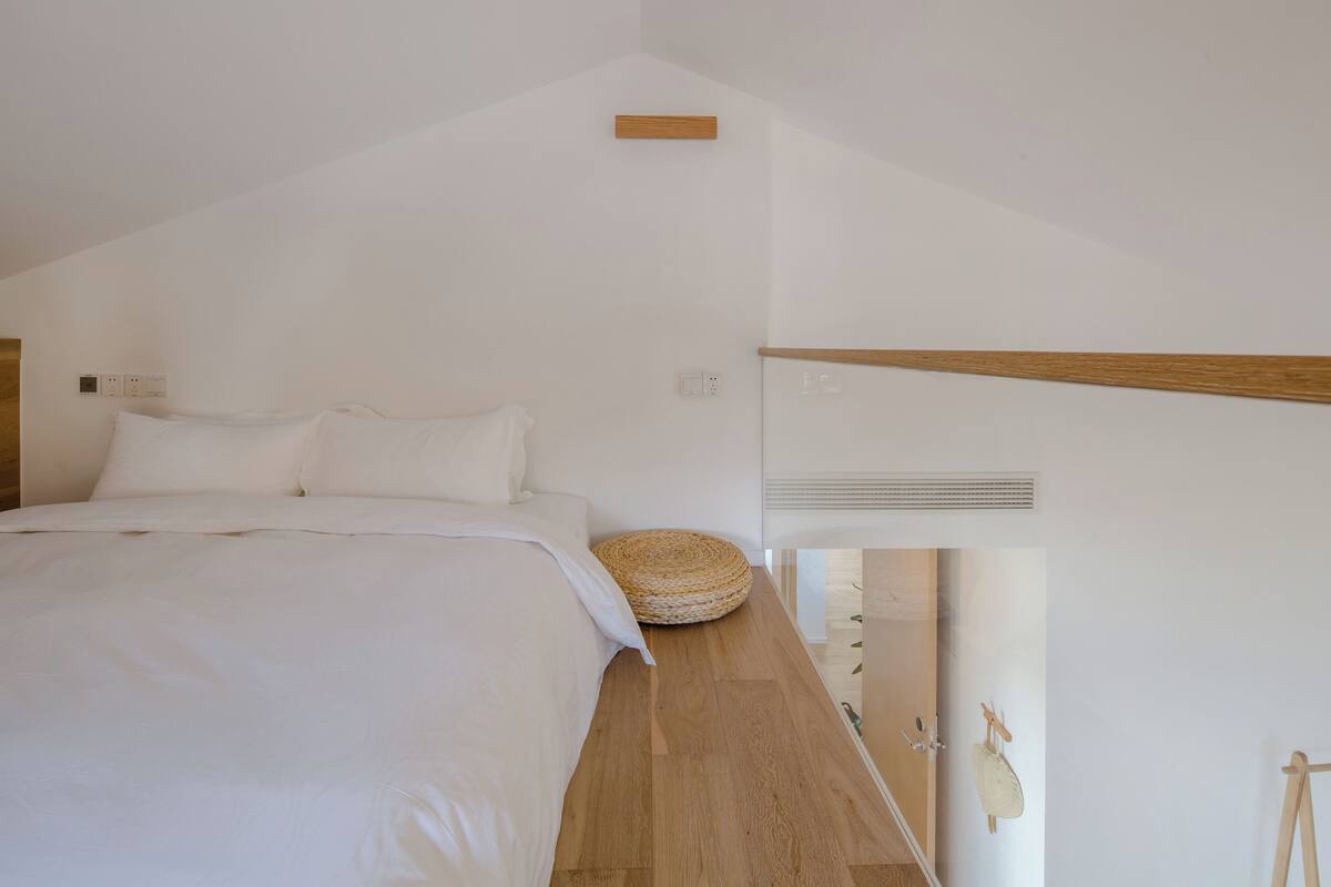Un dormitorio minimalista con una cama grande, una mesita de noche de madera y una cesta tejida.