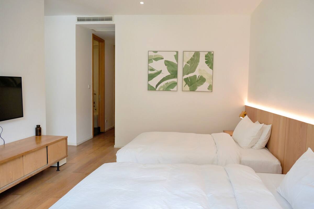 Habitación de hotel con dos camas, televisión y cuadros en la pared.