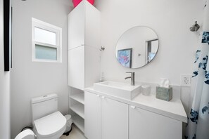 Ein modernes Badezimmer mit Waschbecken, Spiegel und Toilette in Weiß.
