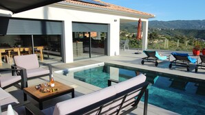 A modern outdoor pool area with lounge chairs, a table, and a view of the mountains. - Villa d'exception piscine privée 🏝️ 300m² - 16 pers Promo en cours (Pietrosella)