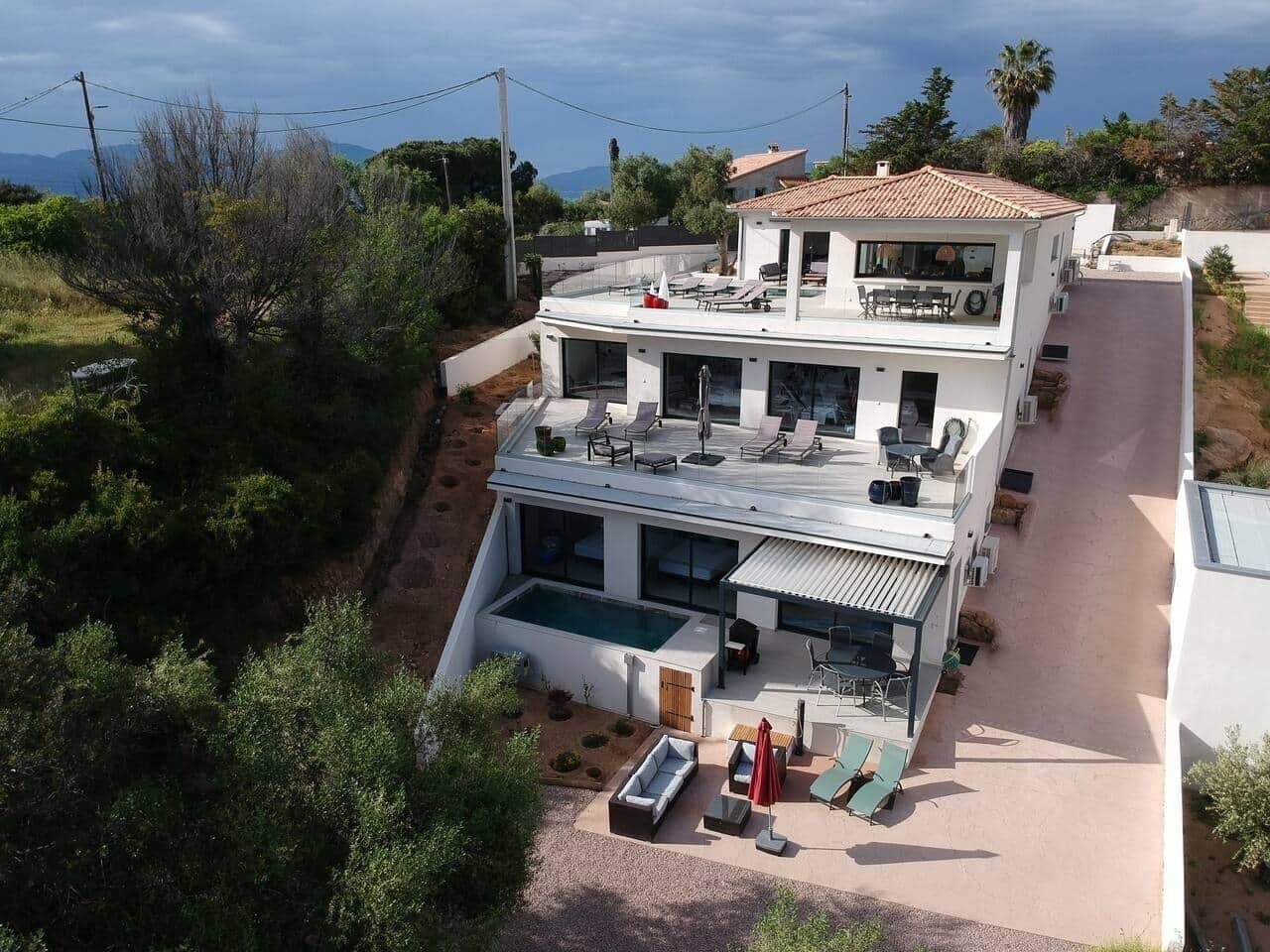 A modern two-story house with a rooftop terrace, a swimming pool, and a patio area.