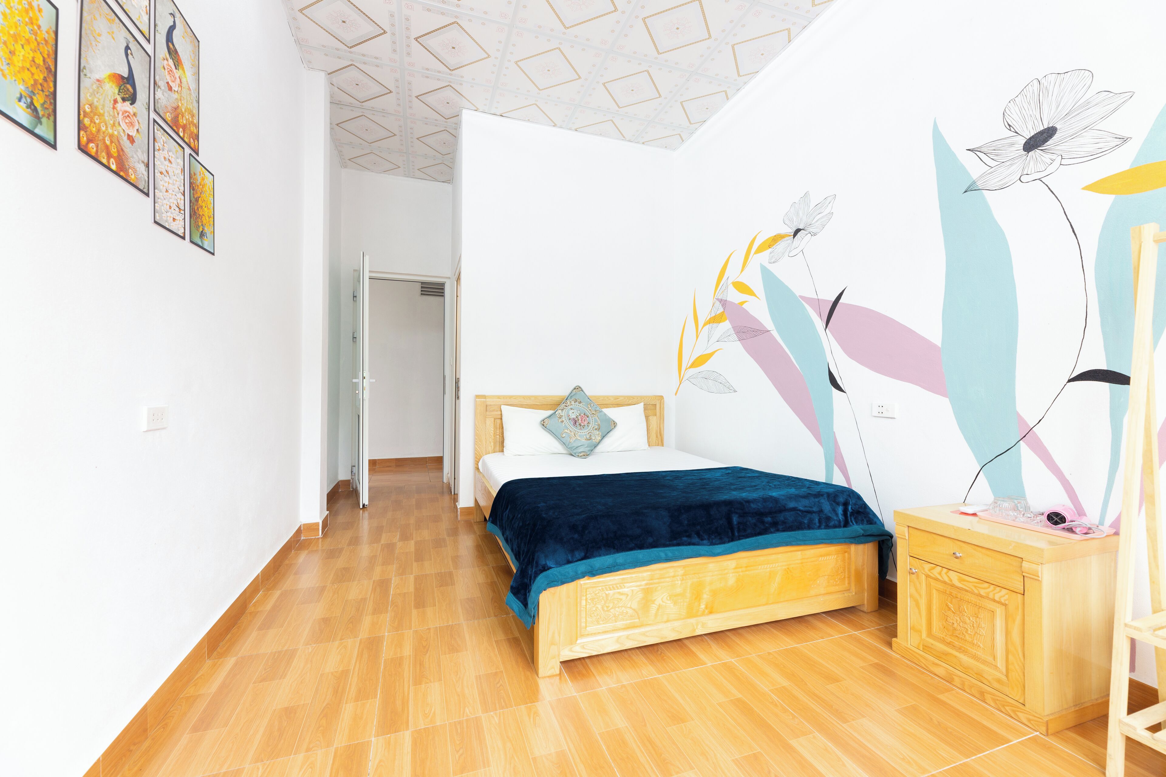 A bedroom with a wooden bed, a nightstand, and a wall with floral artwork.