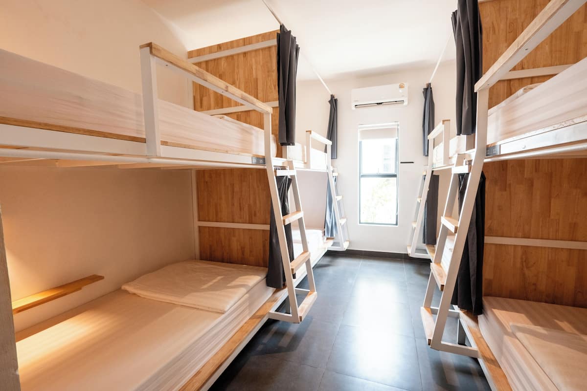 Una habitación con literas, paredes de madera y una ventana con cortinas.