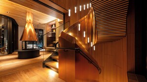 Een modern interieur met een houten trap, een centraal lichtarmatuur en een vloeiend wandontwerp.