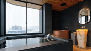 Een moderne badkamer met een groot raam, een badkuip en een marmeren wastafel.